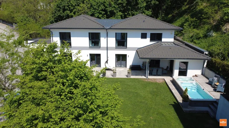 Luftaufnahme eines modernen Hauses mit großem Garten, Rasenfläche und integriertem Pool.