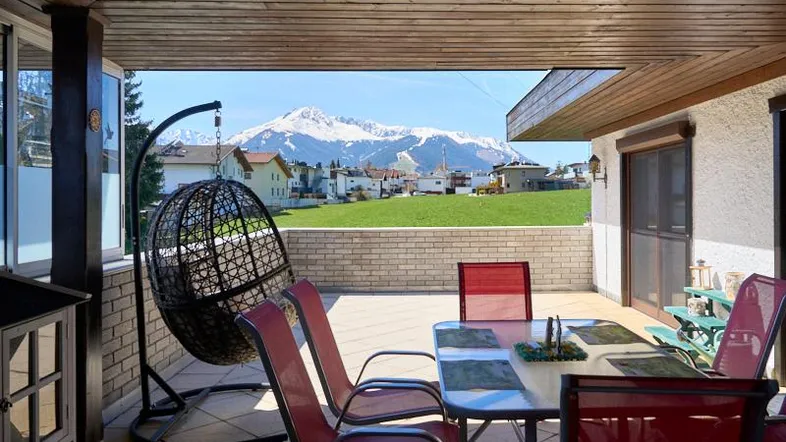 Überdachte Terrasse mit Sitzgelegenheiten und einem weiten Blick auf die umliegende Berglandschaft.