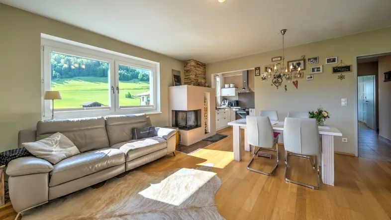 Helles Wohn- und Esszimmer mit modernem Kamin, Holzboden und weitem Blick ins Grüne.