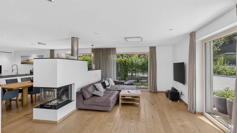Heller, offener Wohn- und Essbereich mit modernem Kamin, Holzboden und Zugang zur Terrasse.