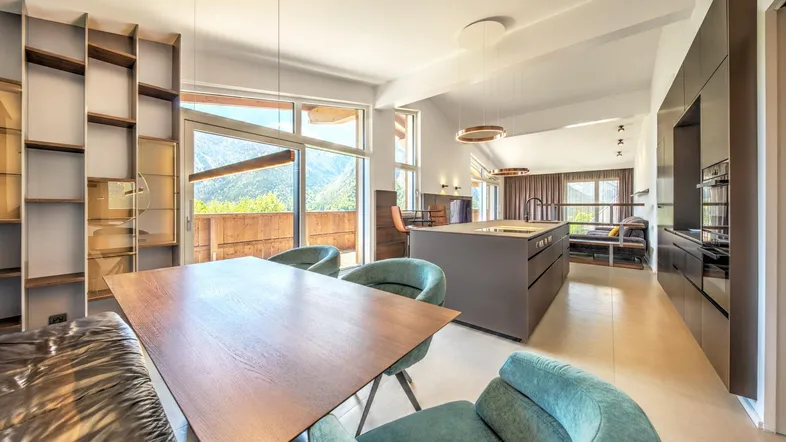 Helles, offenes Wohn-Esszimmer mit moderner Küche, Esstisch und beeindruckendem Bergblick.