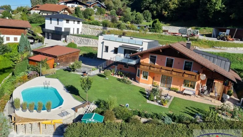 Großzügiger Gartenbereich mit Swimmingpool und Blick auf die umliegende Landschaft und weitere Häuser.