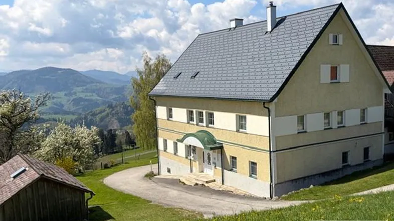 Traditionelles Haus in ländlicher Umgebung mit Bergblick und gepflegtem Gartenbereich.