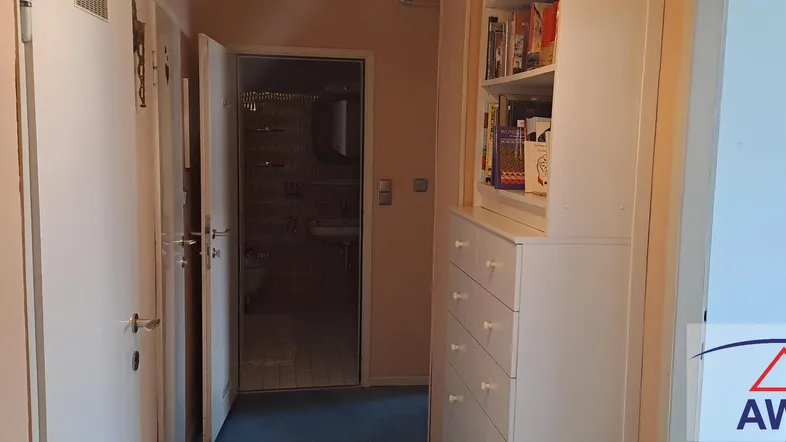 Heller Flur mit Zugang zu einem Badezimmer und einem praktischen Bücherregal.