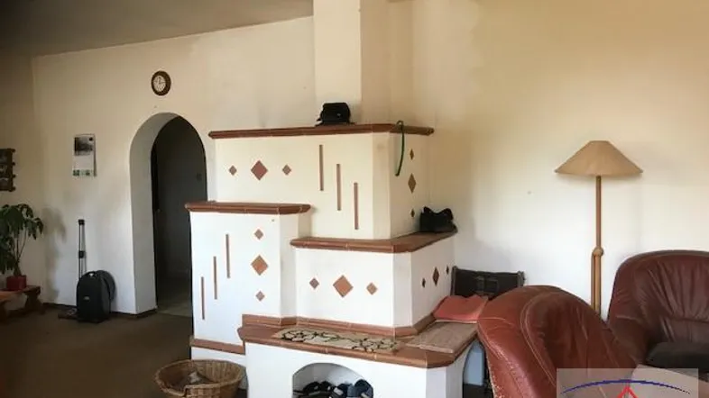 Gemütliches Wohnzimmer mit traditionellem Kachelofen, Ledersofa und warmem Licht.
