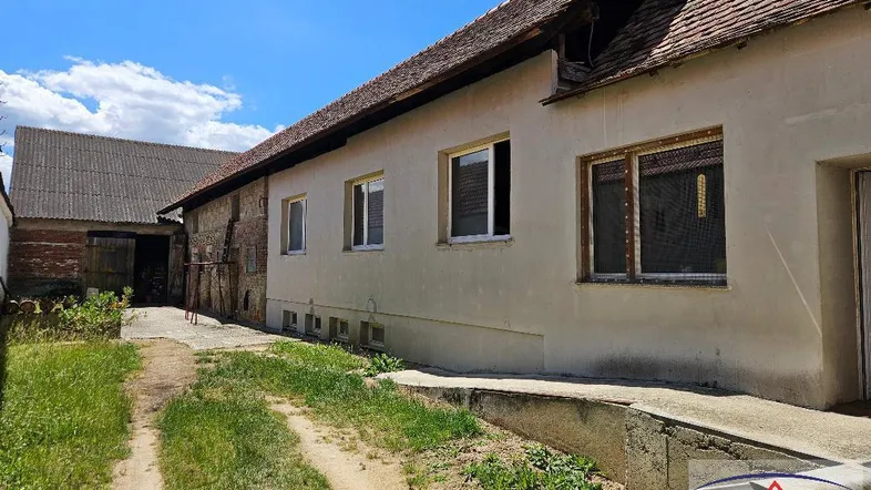 Altes ländliches Gebäude mit einfacher Fassade und einem unbefestigten Weg im Vordergrund.