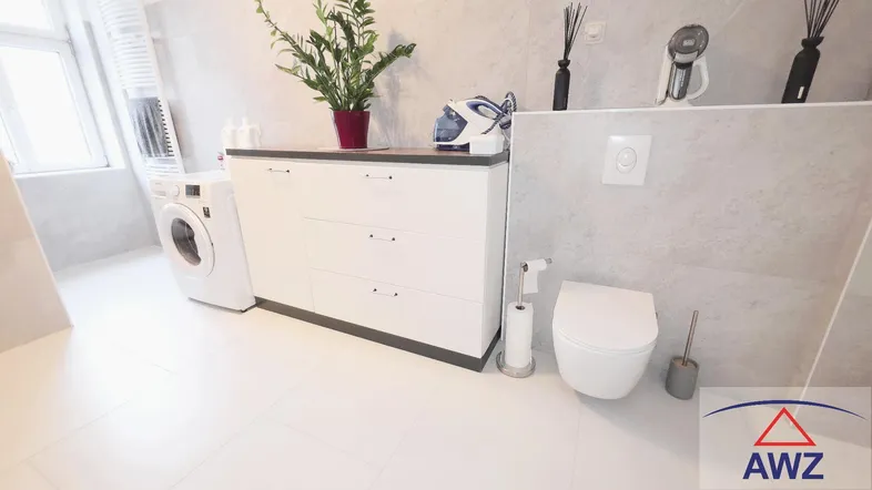 Modernes Badezimmer mit WC, Waschmaschine und einem Fenster für Tageslicht und Belüftung.