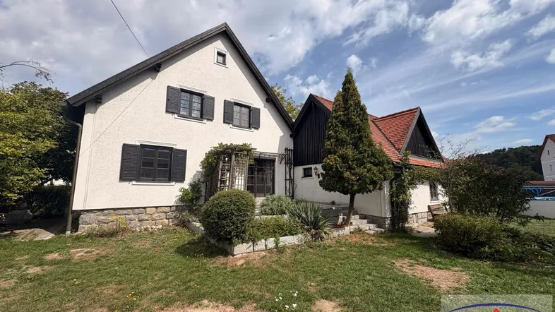 Charmantes Einfamilienhaus mit weißer Fassade, Satteldach und gepflegtem Vorgarten unter blauem Himmel.