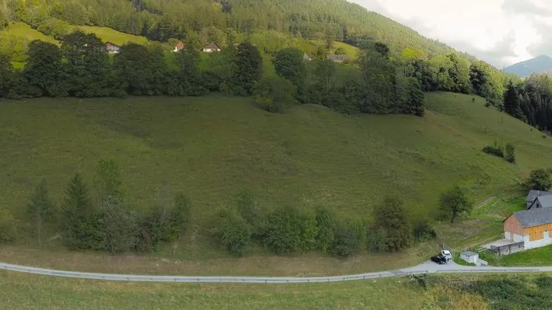 Panoramablick aus der Vogelperspektive auf ein Anwesen in einer grünen Berglandschaft mit umliegenden Wäldern.
