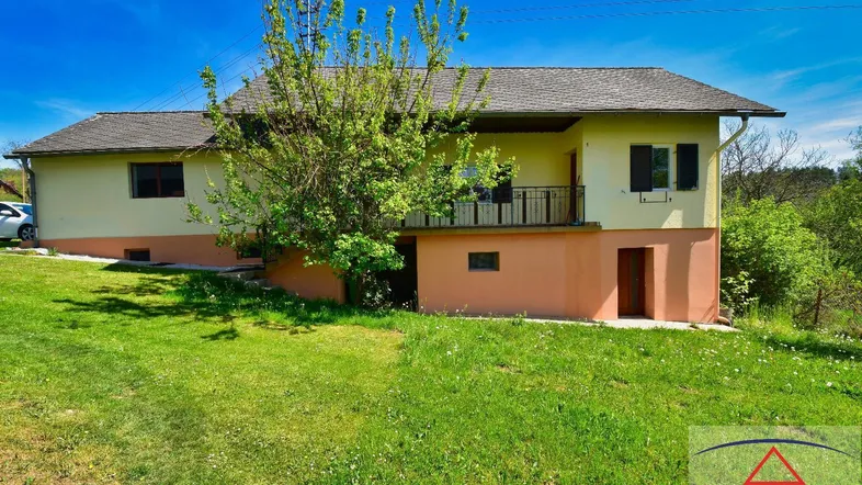 Ansicht des Hauses von außen mit einem kleinen Balkon und einer grünen Rasenfläche.