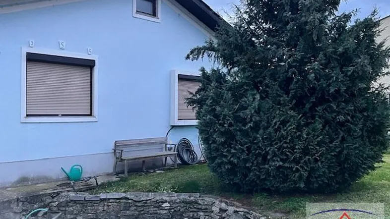 Seitenansicht des Hauses mit Gartenbereich, einer Sitzbank und einem kleinen Teich.