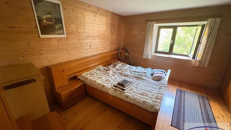 Gemütliches Schlafzimmer mit Holzwänden, Holzboden und Blick ins Grüne.