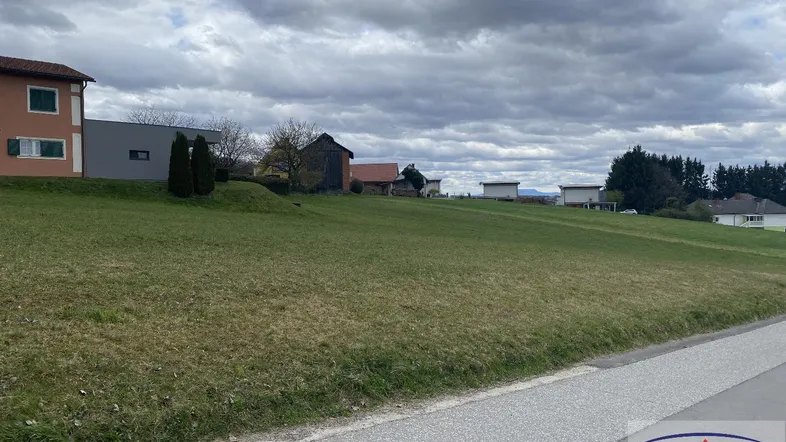 Weitläufiges grünes Grundstück mit Blick auf umliegende Häuser unter bewölktem Himmel.