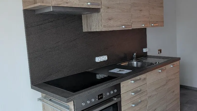 Kompakte Einbauküche mit Holzoptikfronten, Induktionskochfeld und integriertem Backofen.