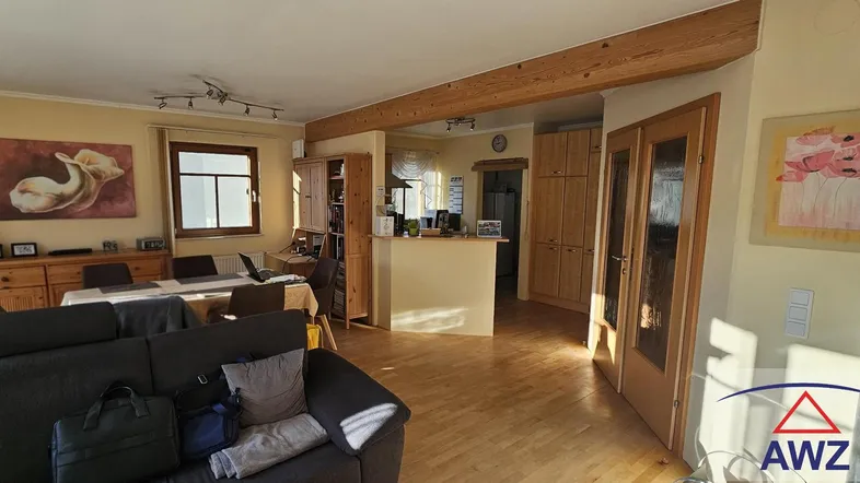 Helles, offenes Wohn- und Esszimmer mit Holzbalken, Parkettboden und viel Tageslicht.