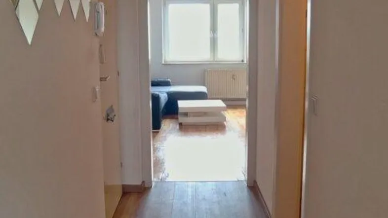 Langer Flur mit Holzfußboden und Zugang zu weiteren Räumen, hell beleuchtet.