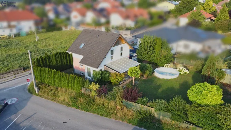 Luftaufnahme des Einfamilienhauses mit gepflegtem Garten, kleinem Pool und umgebender Hecke.
