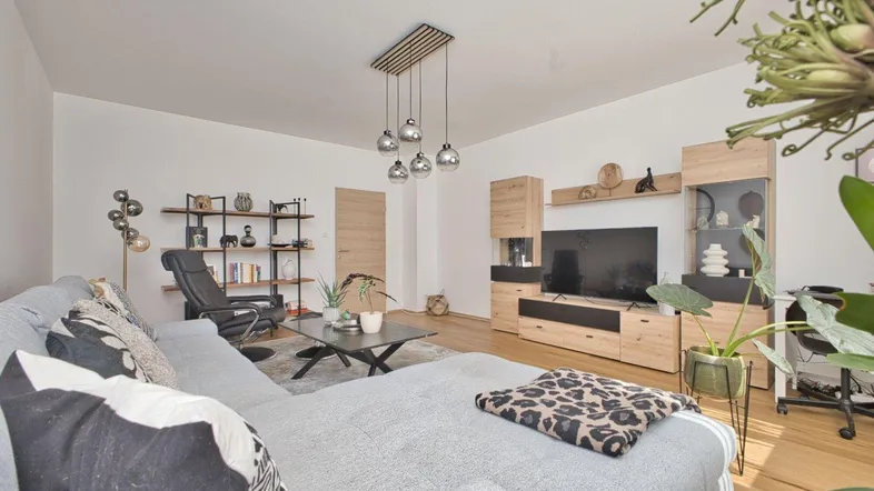 Helles Wohnzimmer mit Holzboden, modernem Sofa und einer stilvollen Medieneinheit.
