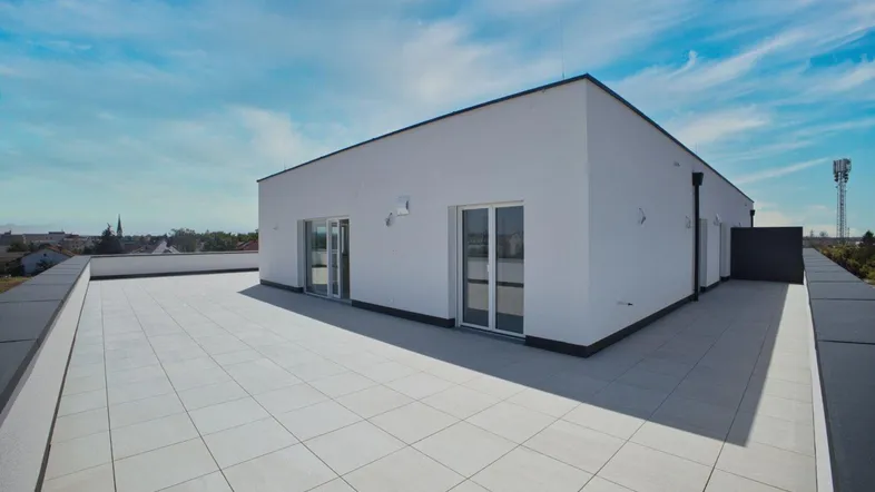 Große, geflieste Dachterrasse mit Zugang zu den Innenräumen und weitem Blick über die Umgebung.
