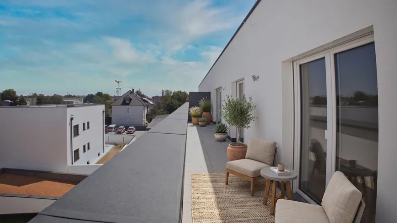 Geräumige Dachterrasse mit modernen Sitzgelegenheiten, Pflanzen und weitem Blick über die Umgebung.