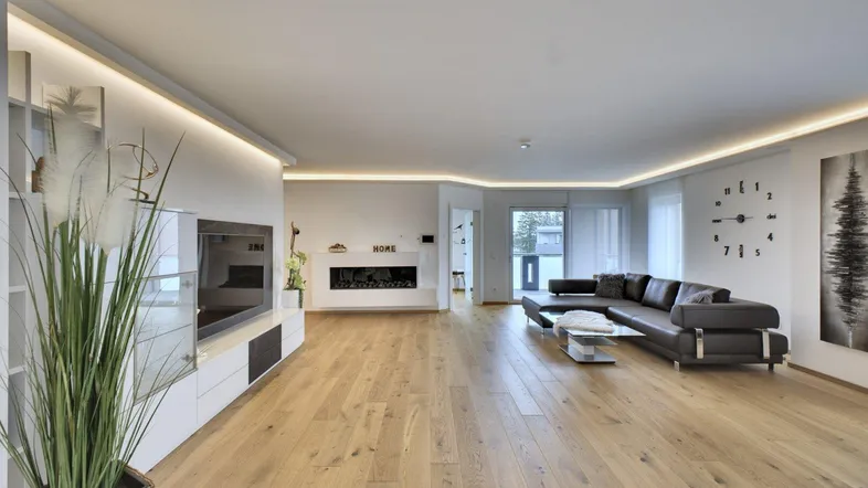 Geräumiges Wohnzimmer mit modernem Sofa, integriertem Kamin und hellem Parkettboden.