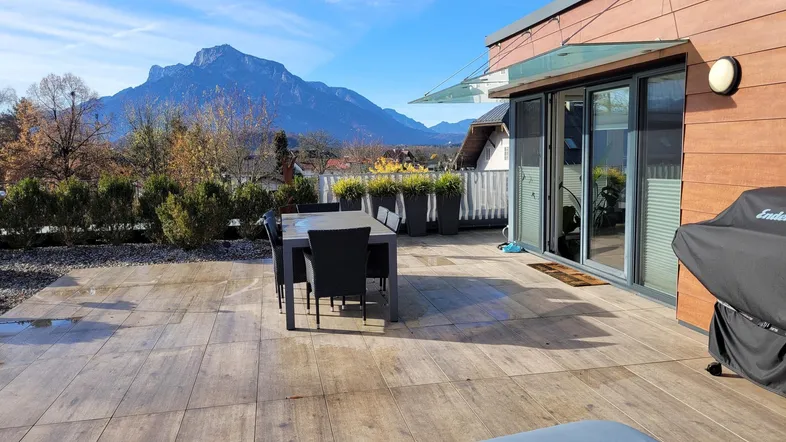 Große Sonnenterrasse mit Essbereich und Liegestühlen, umgeben von einer beeindruckenden Bergkulisse.