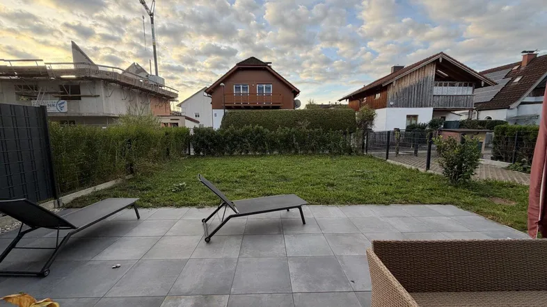 Geräumige Terrasse mit Liegestühlen und Blick auf den Garten und umliegende Häuser.