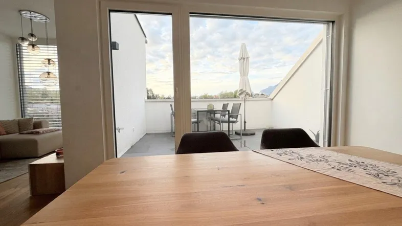 Heller Essbereich mit Holztisch und direktem Zugang zur großzügigen Terrasse mit Bergblick.