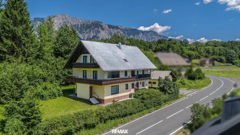 Haus in ländlicher Umgebung mit Bergblick und umliegenden Wäldern.