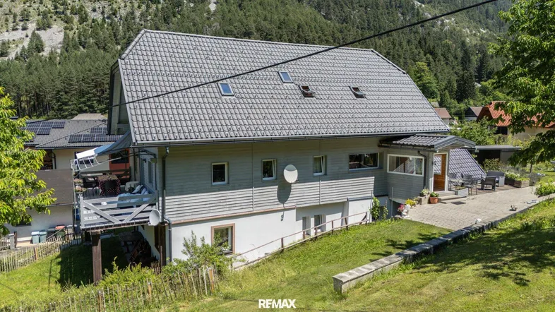 Hausfassade mit Balkon, Satteldach und Blick auf die umliegende Berglandschaft.