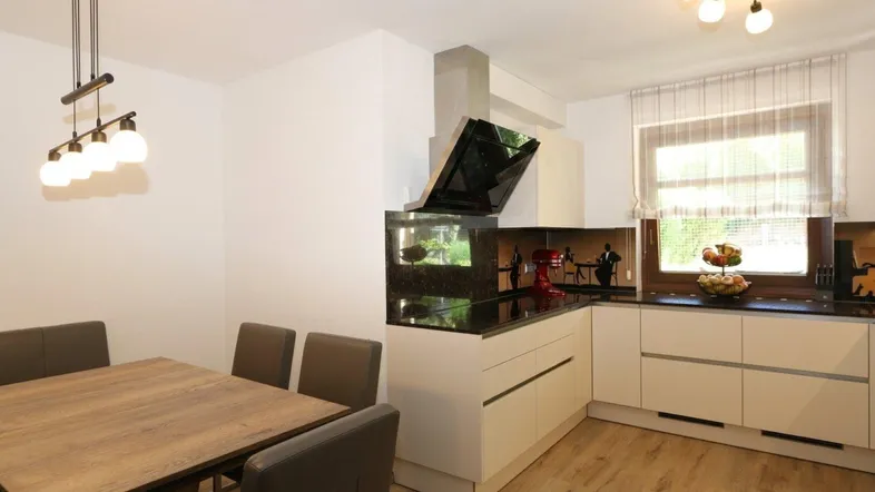 Moderne Küche mit Essbereich, dunkler Arbeitsplatte und integriertem Aquarium, hell beleuchtet.