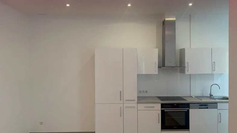 Moderne Einbauküche mit weißen Hochglanzfronten, Granitarbeitsplatte und integrierten Geräten.