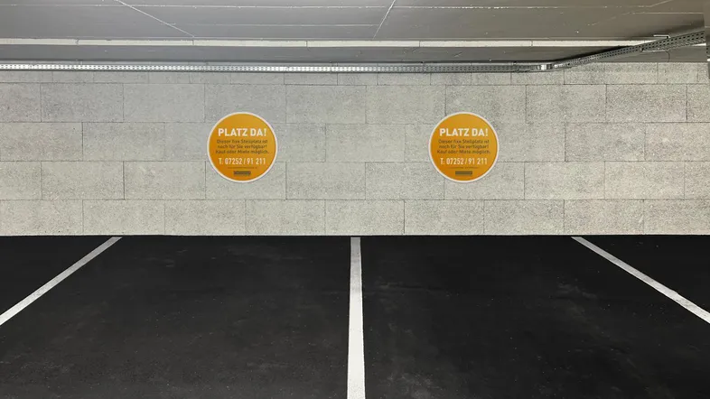 Helle Tiefgarage mit markierten Parkplätzen und modernen Betonwänden und -decken.