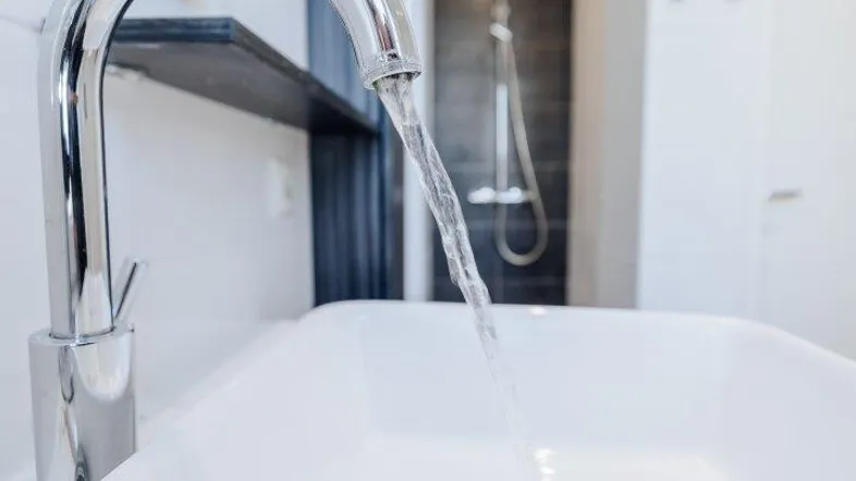 Modernes Badezimmer mit stilvollem Waschbecken und Duschbereich im Hintergrund, hell beleuchtet.