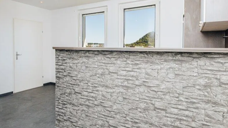 Moderne offene Küche mit Bartheke, Einbaustrahlern und Blick auf die grüne Umgebung.
