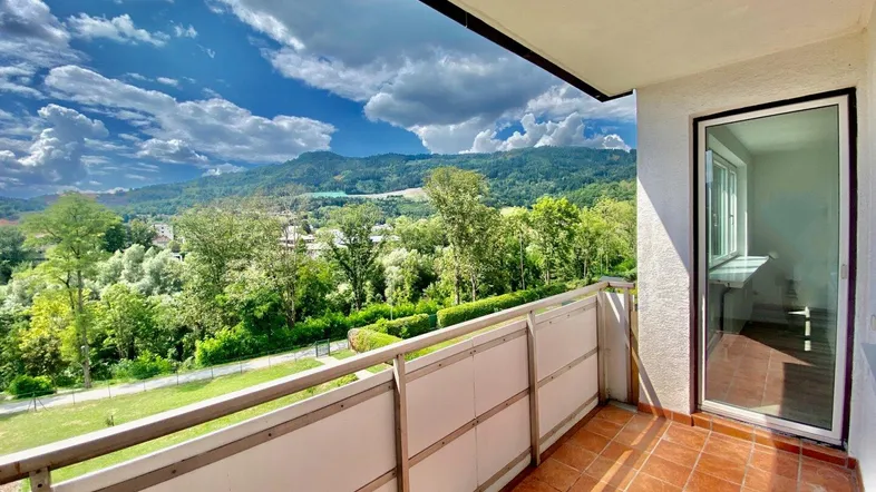 Geräumiger Balkon mit Terrakottafliesen und weitem Blick auf die grüne Landschaft und Berge.