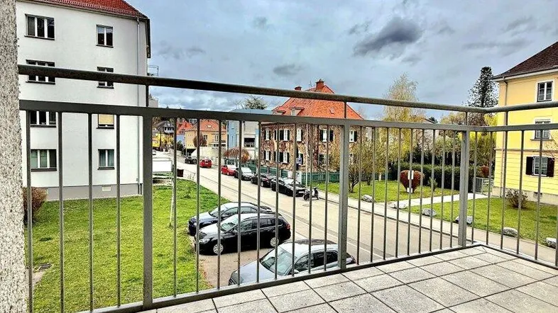 Geräumiger Balkon mit Fliesenboden und Blick auf die umliegende Straße und Gebäude.