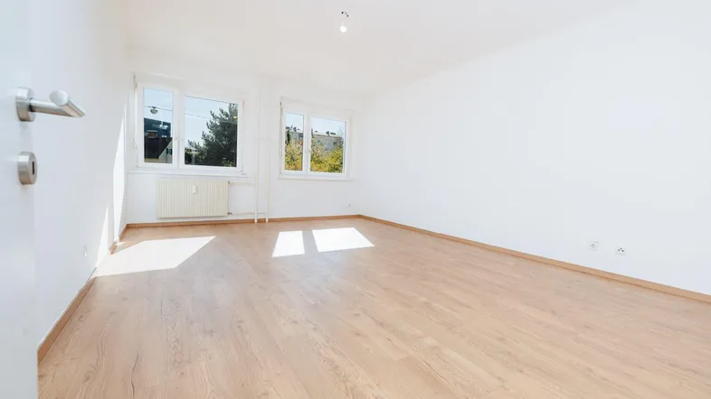 Heller, leerer Raum mit Parkettboden und zwei Fenstern, ideal als Wohn- oder Schlafzimmer.