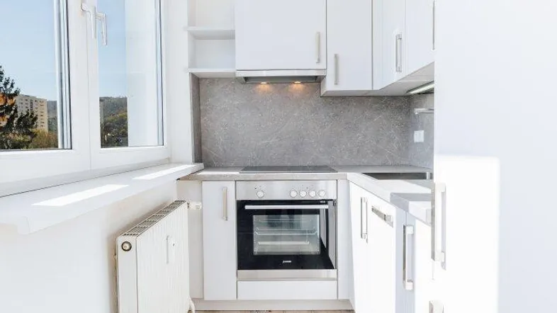 Moderne, helle Küche mit weißen Schränken, integriertem Ofen und Fenster mit Ausblick.