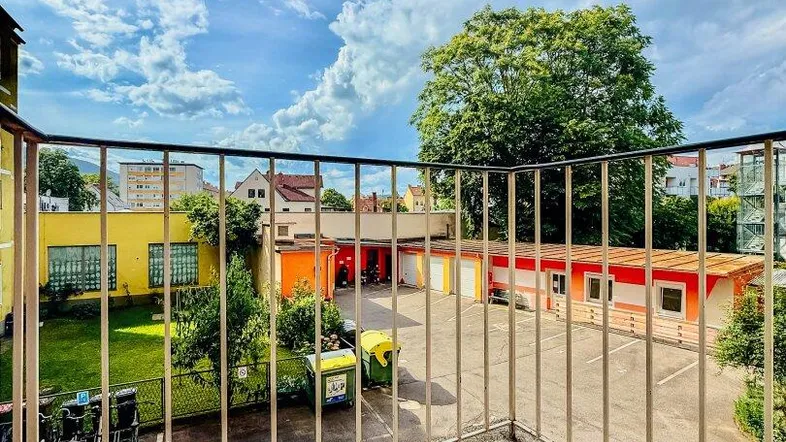 Balkon mit Fliesenboden und Blick auf den Innenhof mit Garagen und umliegenden Gebäuden.