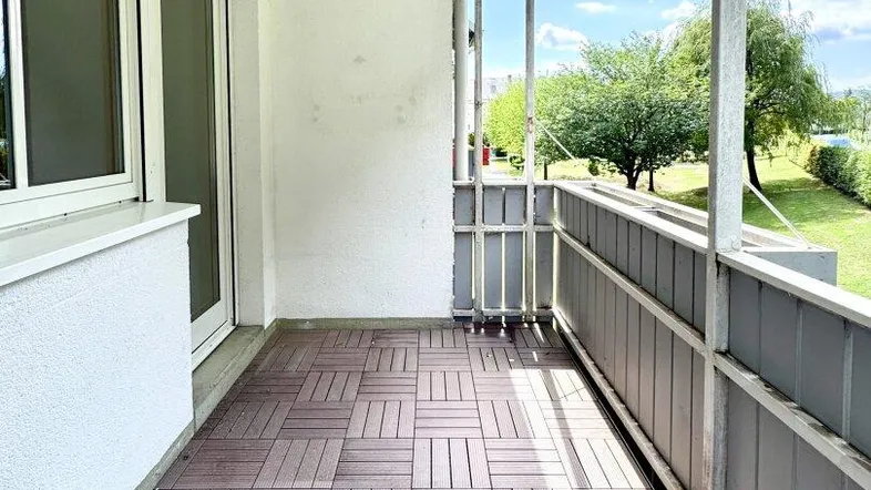 Heller Balkon mit Holzdielenboden und Blick ins Grüne, ideal für entspannte Stunden im Freien.