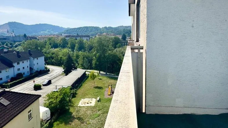 Geräumiger Balkon mit grüner Auslegware und weitem Blick über die Stadt und die umliegende Landschaft.