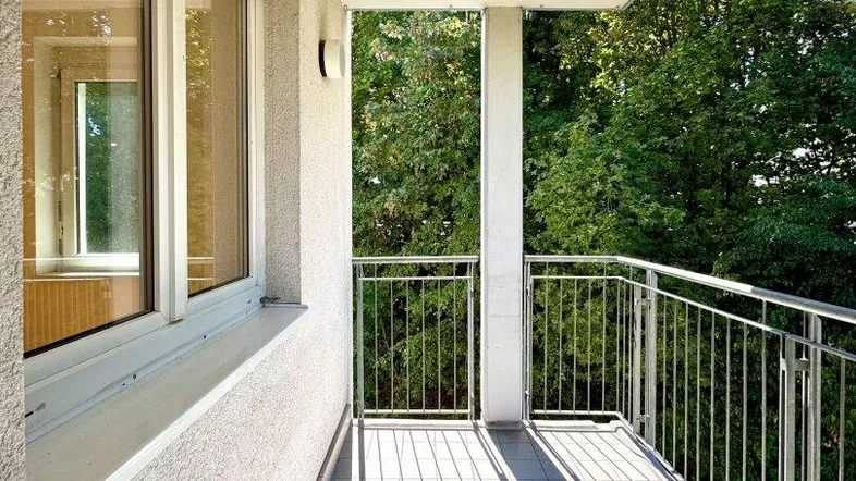 Heller Balkon mit Fliesenboden und Blick ins Grüne, ideal für entspannte Stunden im Freien.
