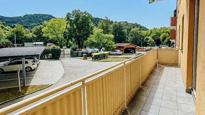 Geräumiger Balkon mit Fliesenboden und Blick auf die grüne Umgebung und Berge.