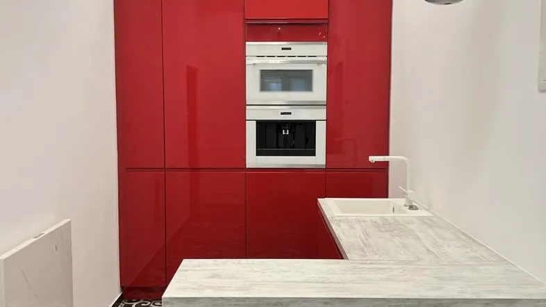 Moderne Küche mit glänzenden roten Schränken, integrierten Geräten und einem markanten schwarz-weißen Fliesenboden.