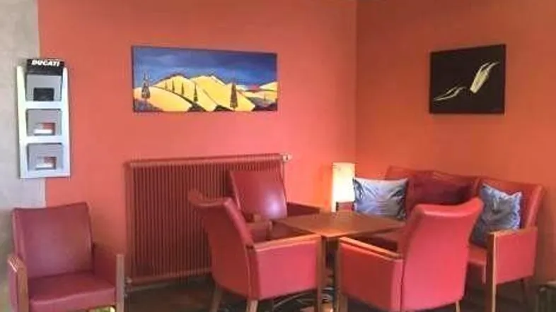 Gemütlicher Loungebereich mit roten Ledersesseln und indirekter Beleuchtung auf einer erhöhten Plattform.
