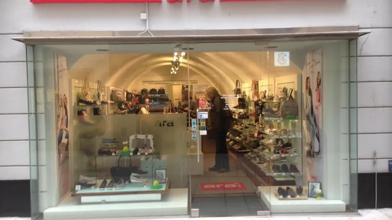 Vorderansicht eines Schuhgeschäfts mit großer Glasfront und einem Kunden im Inneren.