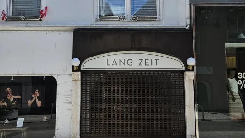 Fassade eines Geschäftsgebäudes mit einem geschlossenen Ladenlokal im Erdgeschoss und Fenstern im Obergeschoss.
