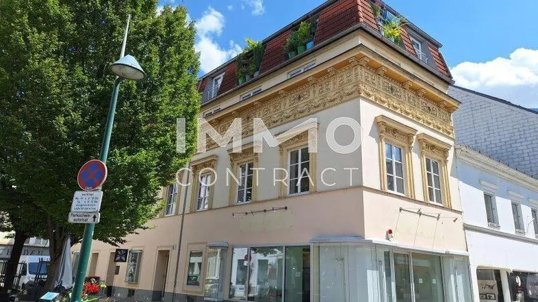 Historisches Gebäude mit aufwendiger Fassadenverzierung und Dachterrasse in städtischer Umgebung.