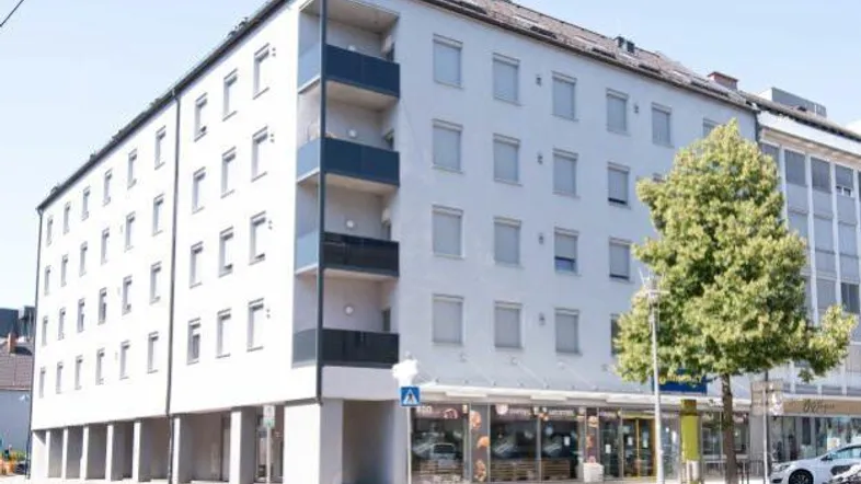 Modernes Mehrfamilienhaus mit Geschäften im Erdgeschoss und Balkonen an der Fassade.